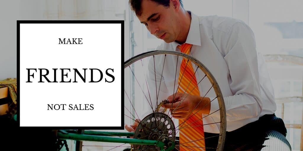 Build Lasting Client Relationships: Make Friends Not Sales. Picture: Business man in suit with jacket off fixing his bicycle tire.