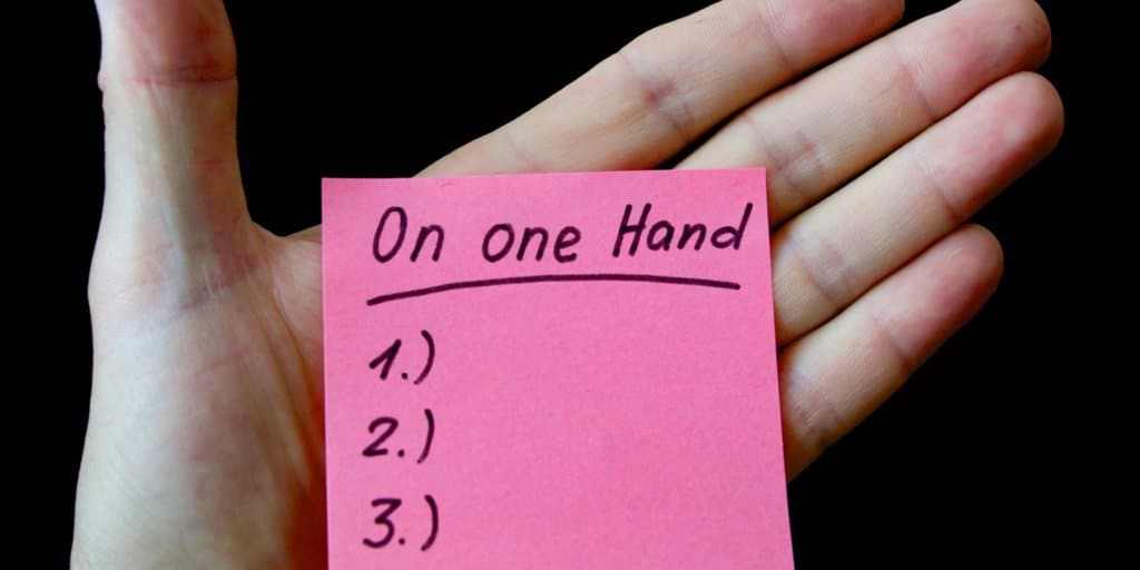 Hand with a sticky note list on it.
